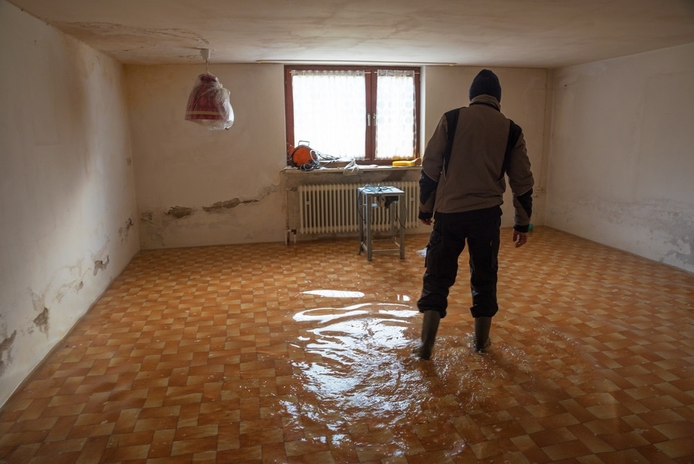 man standing with boots in the middle of a flooded basement